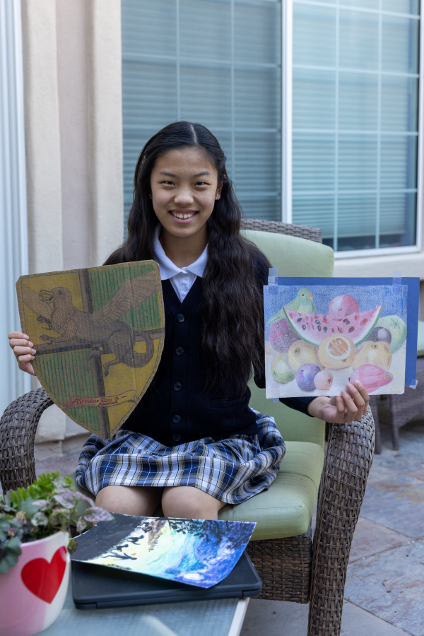 A student proudly showing her artwork to her online class